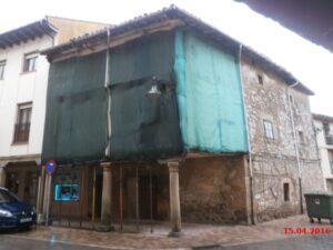 Edificio en mal estado con andamios y lona en Aguilar de Campoo