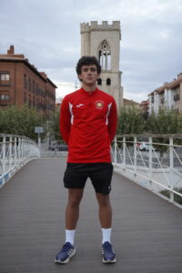 Joven atleta Diego Zorita posando en un puente con su uniforme deportivo.