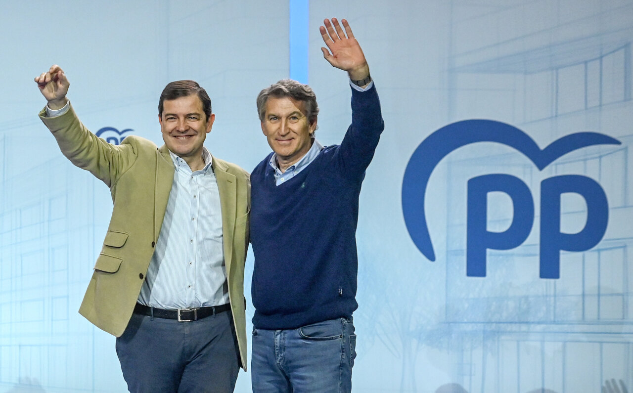 Líderes del PP en un evento político levantando la mano.