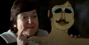 Escena de la película El espíritu de la colmena con un personaje mostrando una figura de madera.