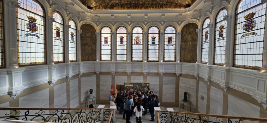 Interior de un edificio con vitrales y un grupo de personas reunidas