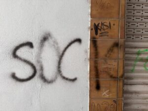 Grafiti en una pared con la palabra SOCIO escrita en negro