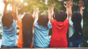 Grupo de niños levantando las manos al aire en un parque