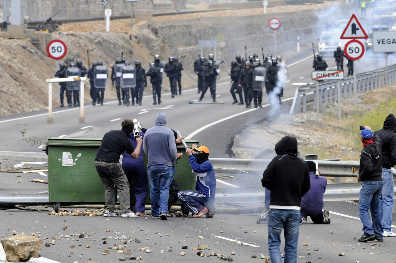 Protesta en carretera con manifestantes y policía en el fondo