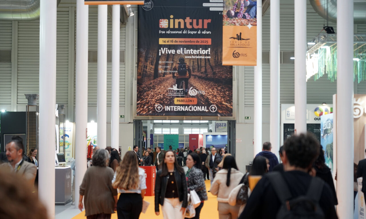 Visitantes en la Feria Intur de Valladolid con un gran cartel de bienvenida.