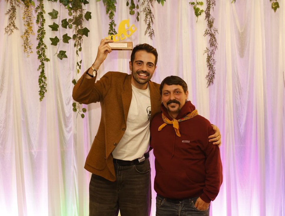 Kike García y Castora Herz sosteniendo un premio en un evento