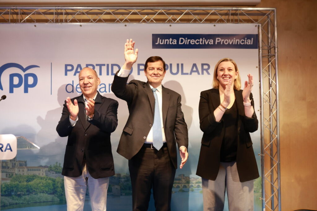 El presidente del PPCyL junto a otros miembros del partido aplaudiendo en un evento
