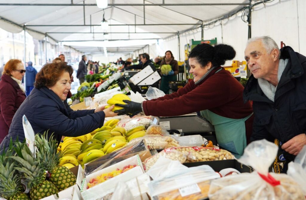 Clientes comprando frutas y verduras en un mercado local