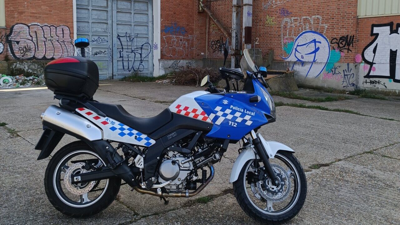 Moto de la Policía Local estacionada en un área urbana con grafitis.