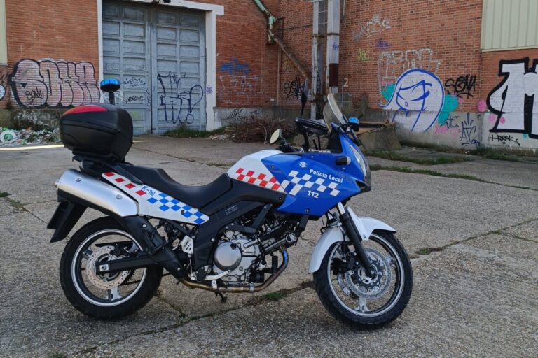 Moto de la Policía Local estacionada en un área urbana con grafitis.