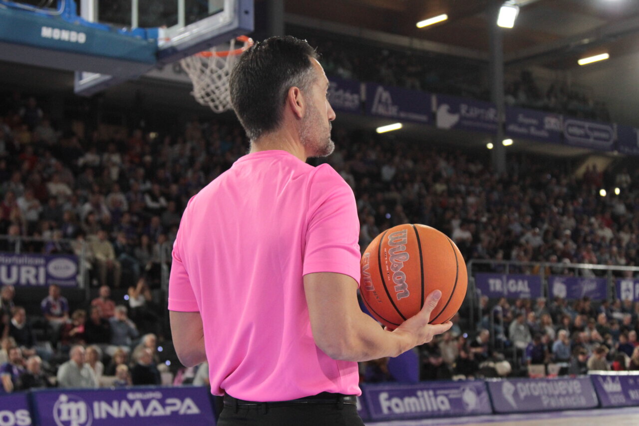 Árbitro sosteniendo un balón de baloncesto en un partido