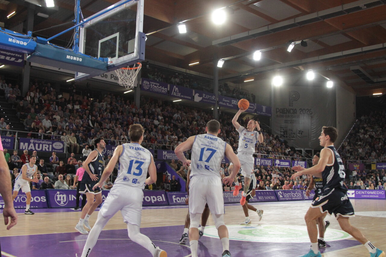 Jugador lanzando a canasta durante un partido de baloncesto en Palencia