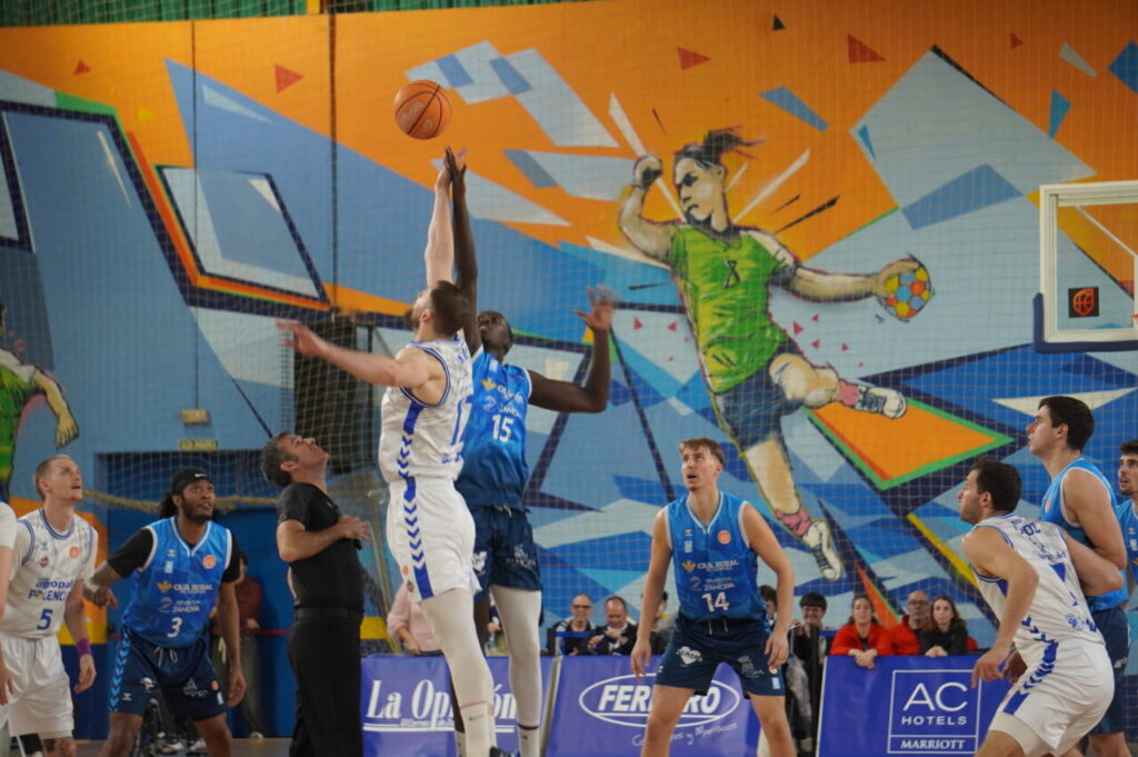 Jugadores de baloncesto en un salto inicial durante un partido.