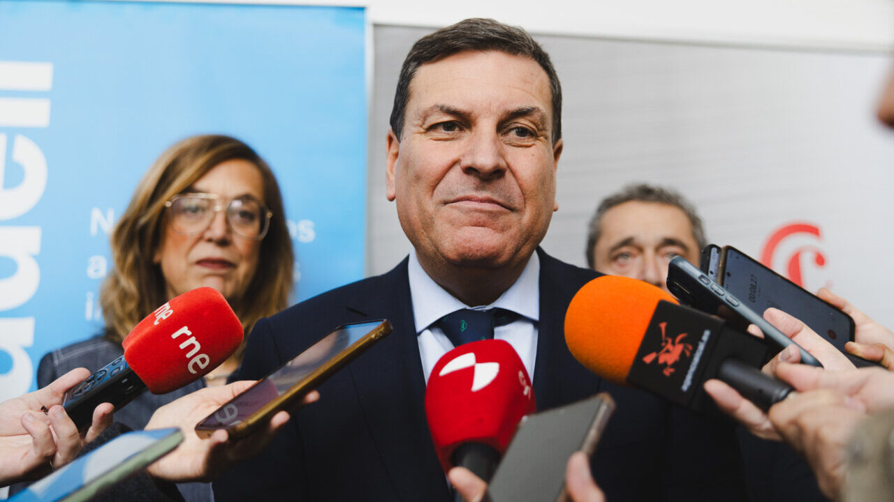 Carriedo hablando en una conferencia rodeado de periodistas