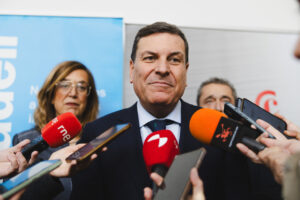 Carriedo hablando en una conferencia rodeado de periodistas