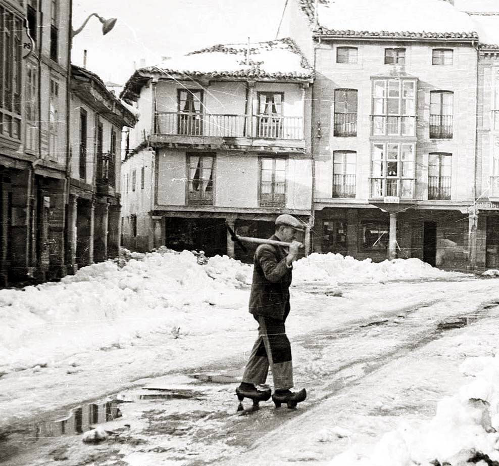 Hombre caminando con esquís en una calle nevada