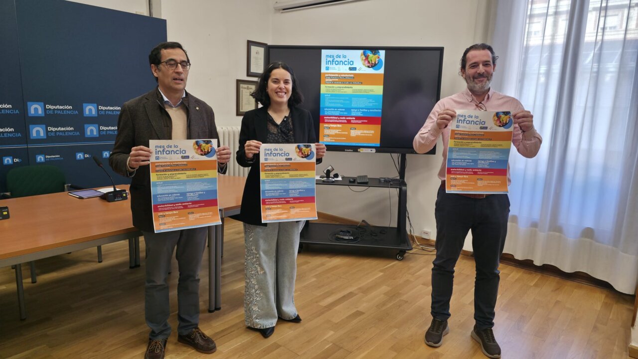Tres personas sosteniendo carteles sobre el Mes de la Infancia en Palencia.