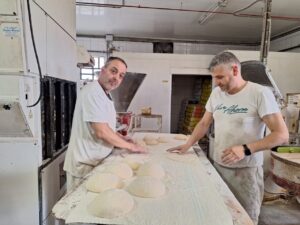 Dos panaderos trabajando la masa en un obrador tradicional.