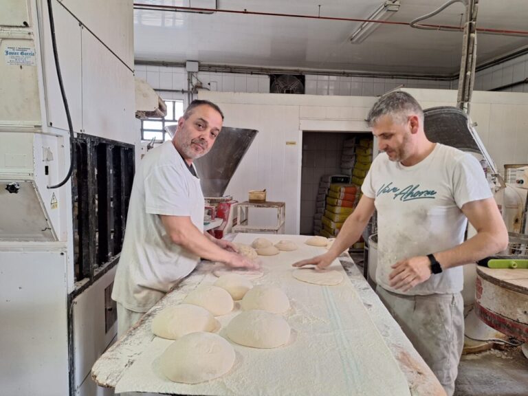 Dos panaderos trabajando la masa en un obrador tradicional.