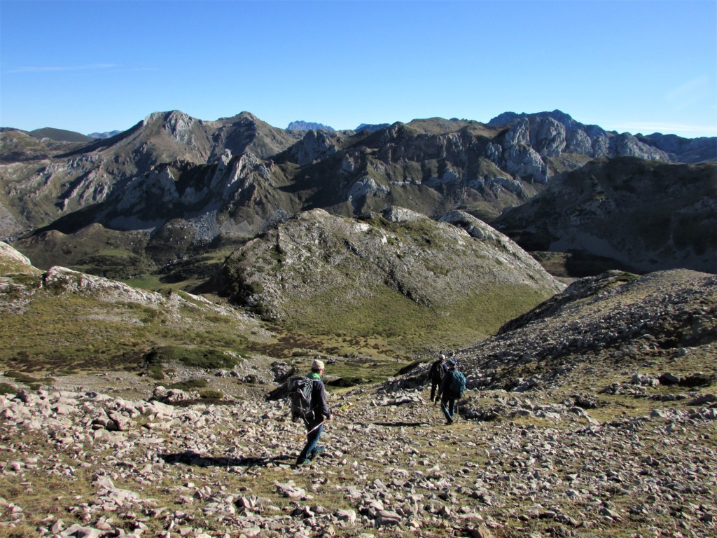 Montañeros caminando por la Cordillera Cantábrica en un día soleado.