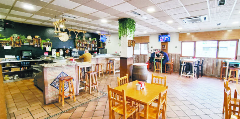 Interior del restaurante Come y Bebe con mesas y barra.