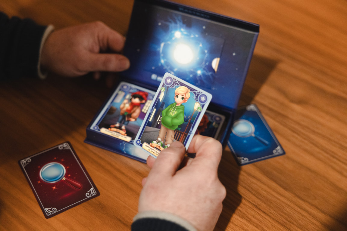 Un padre y su hijo jugando con cartas del juego Rastreo en una mesa de madera.