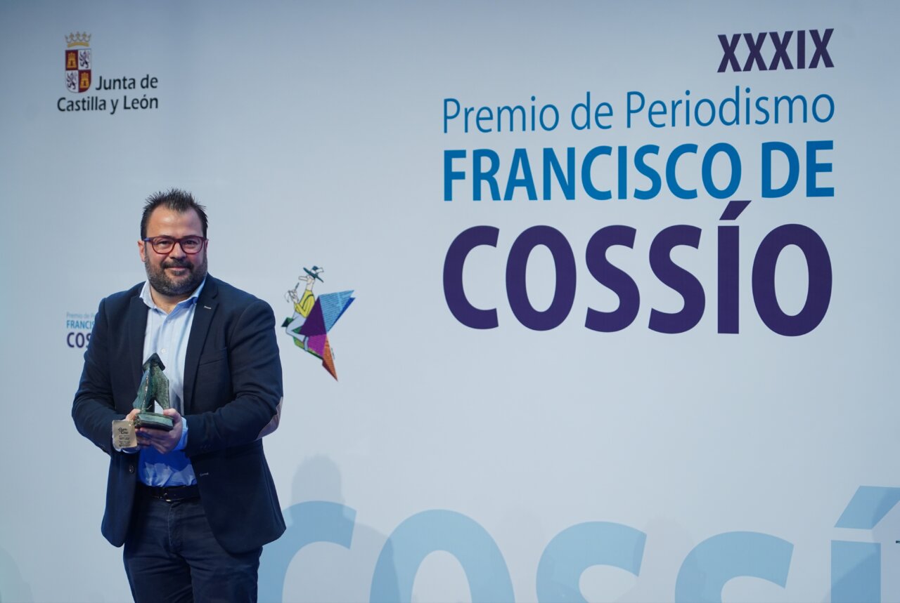 Hombre sosteniendo un premio en un evento de periodismo
