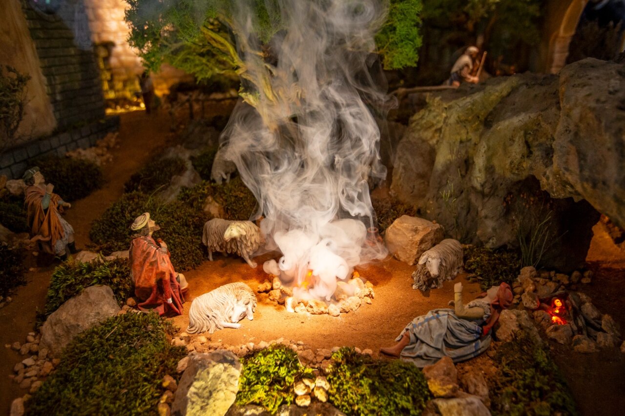 Representación del belén con figuras y humo en un entorno natural