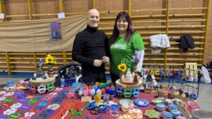 Dos personas sonriendo en un mercadillo solidario con artesanías