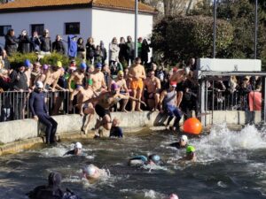 Participantes saltando al agua en una competencia de natación en invierno