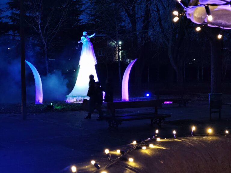 Escena nocturna del Jardín de la Fantasía con luces y personajes
