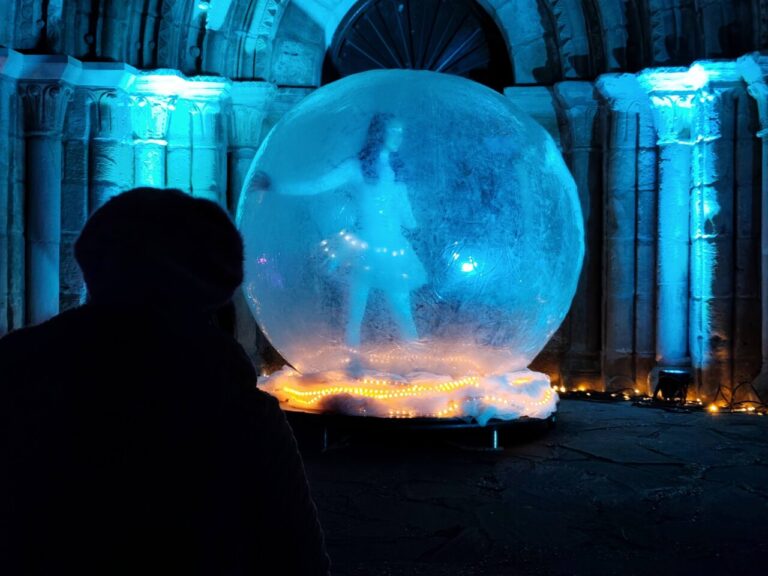 Persona observando una figura en una burbuja iluminada en el Jardín de la Fantasía