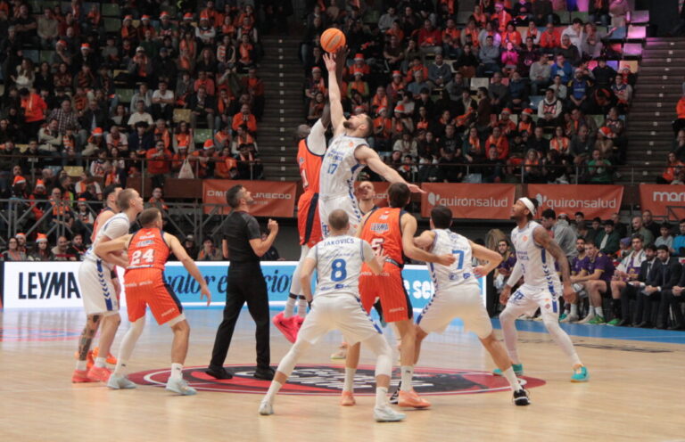 Jugadores saltando para el salto inicial en un partido de baloncesto