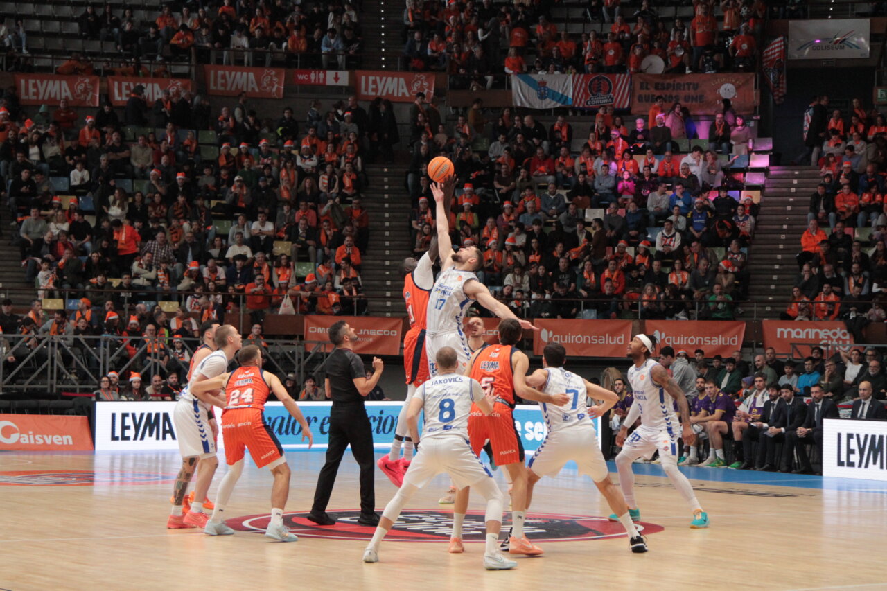 Jugadores saltando para el salto inicial en un partido de baloncesto