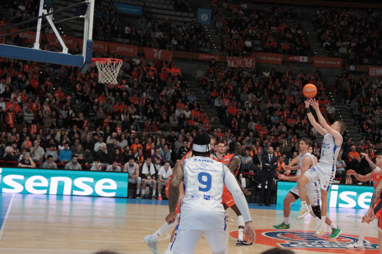 Jugador lanzando a canasta en un partido de baloncesto