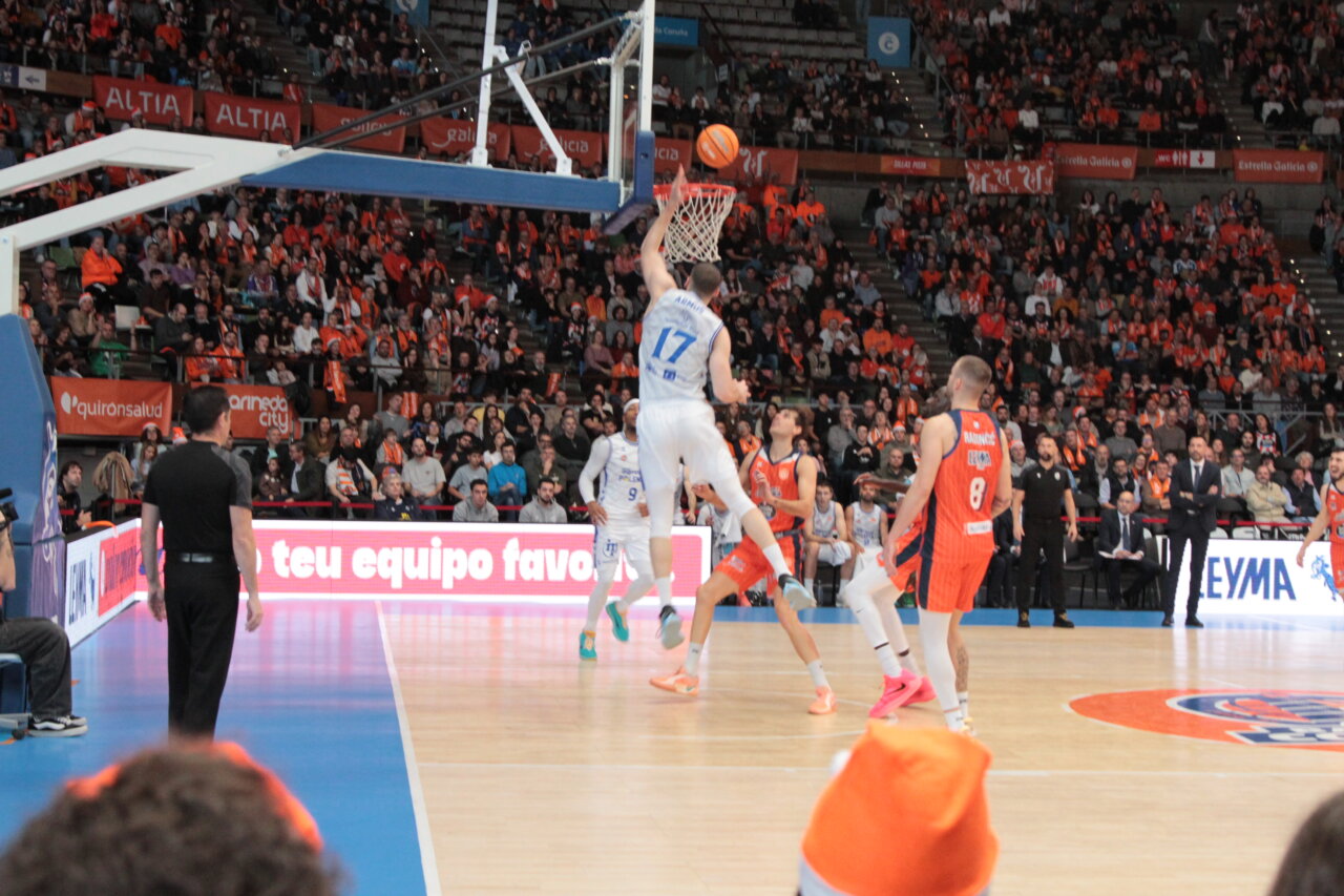 Jugador saltando para encestar en un partido de baloncesto