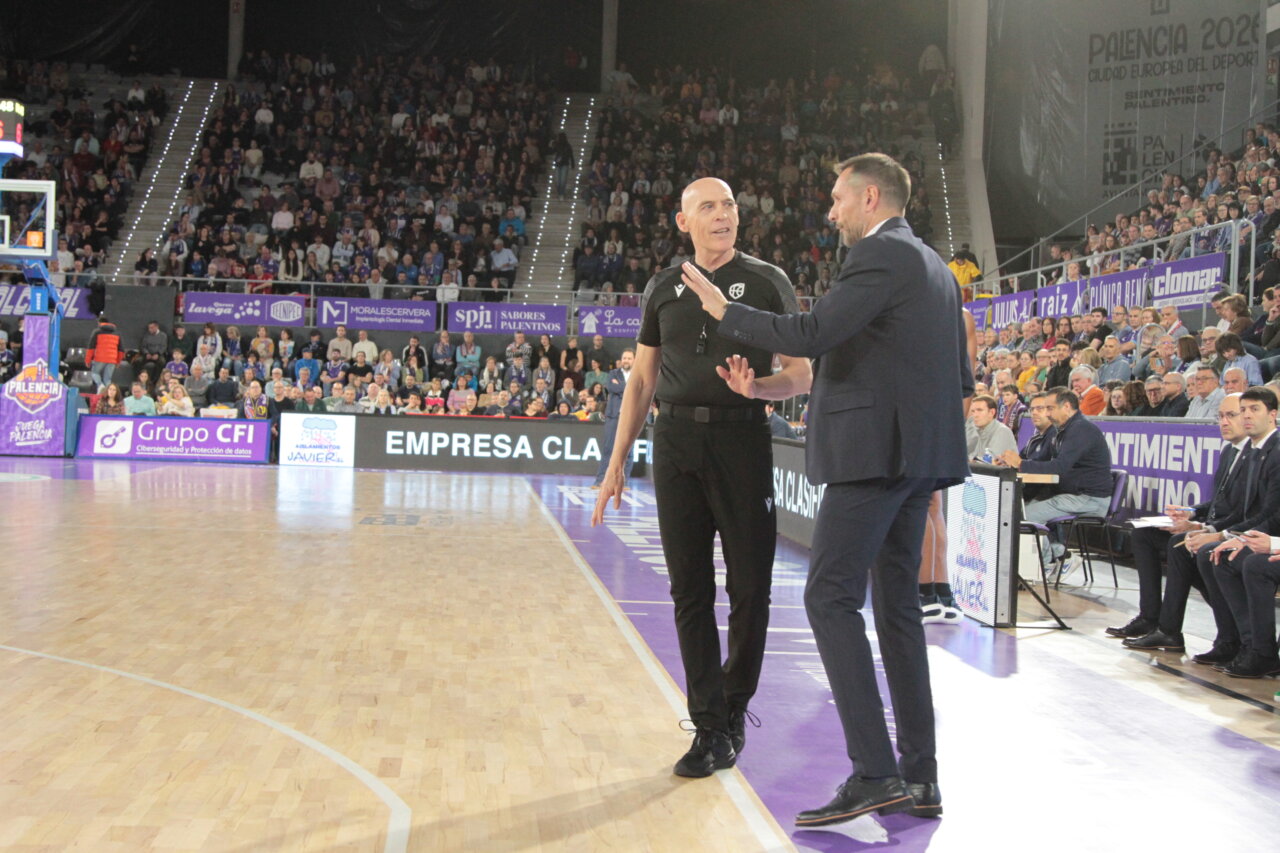 Entrenador y árbitro conversando durante un partido de baloncesto en Palencia