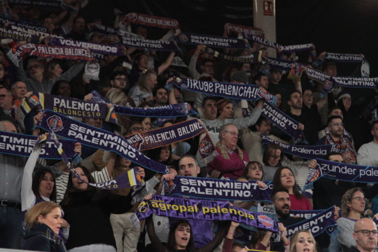 Aficionados del baloncesto sosteniendo bufandas en las gradas