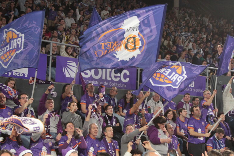 Aficionados animando con banderas en un partido de baloncesto