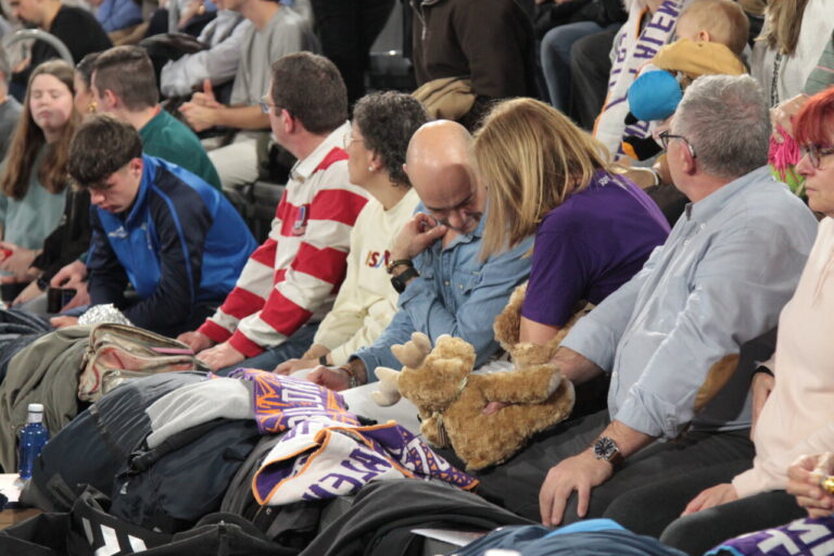 Espectadores en un partido de baloncesto con peluches y ropa de equipo