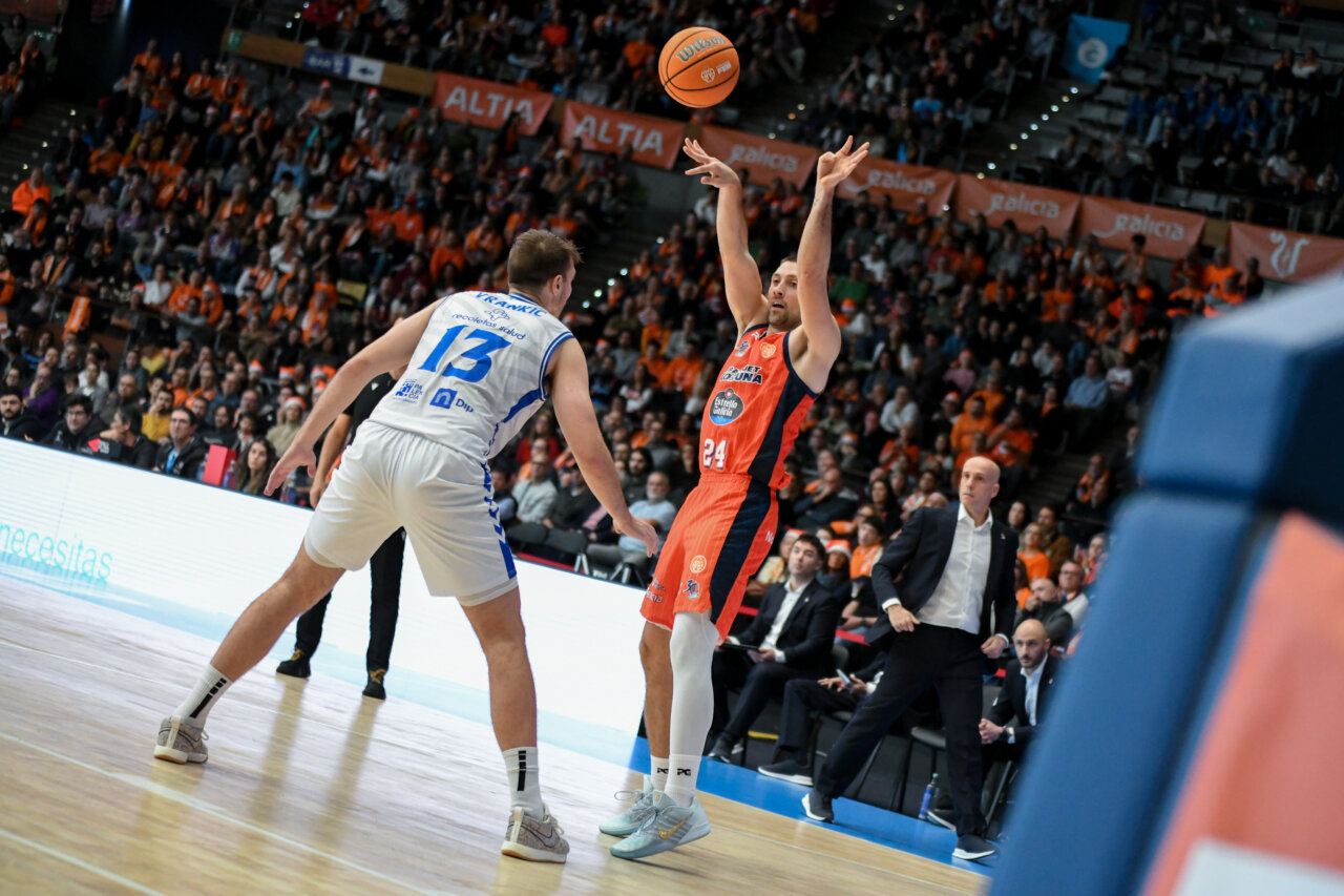 Jugador lanzando un balón de baloncesto en un partido intenso