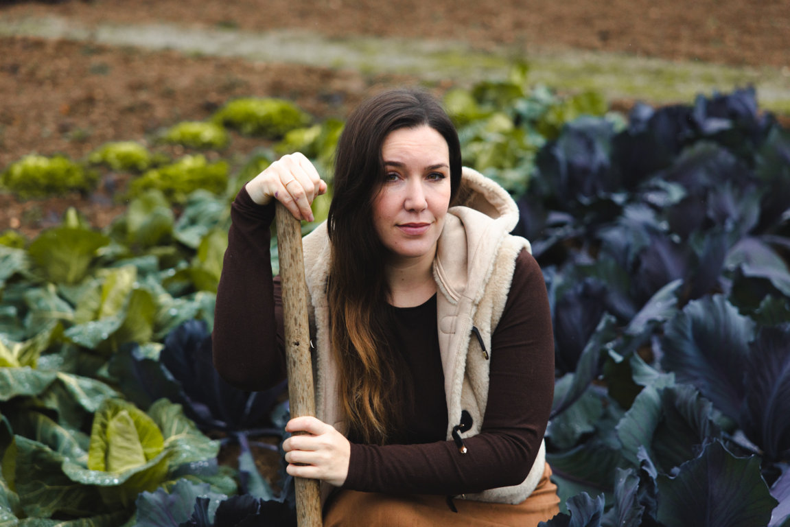 Mujer en huerta sostenible con vegetales frescos y pala