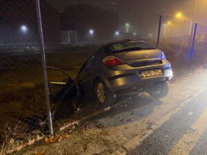 Vehículo accidentado al borde de un camino con una valla