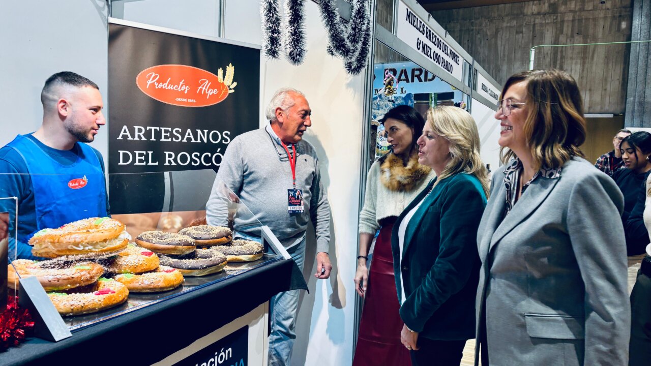 Stand de productos de Palencia en feria gastronómica con dulces y personas conversando.