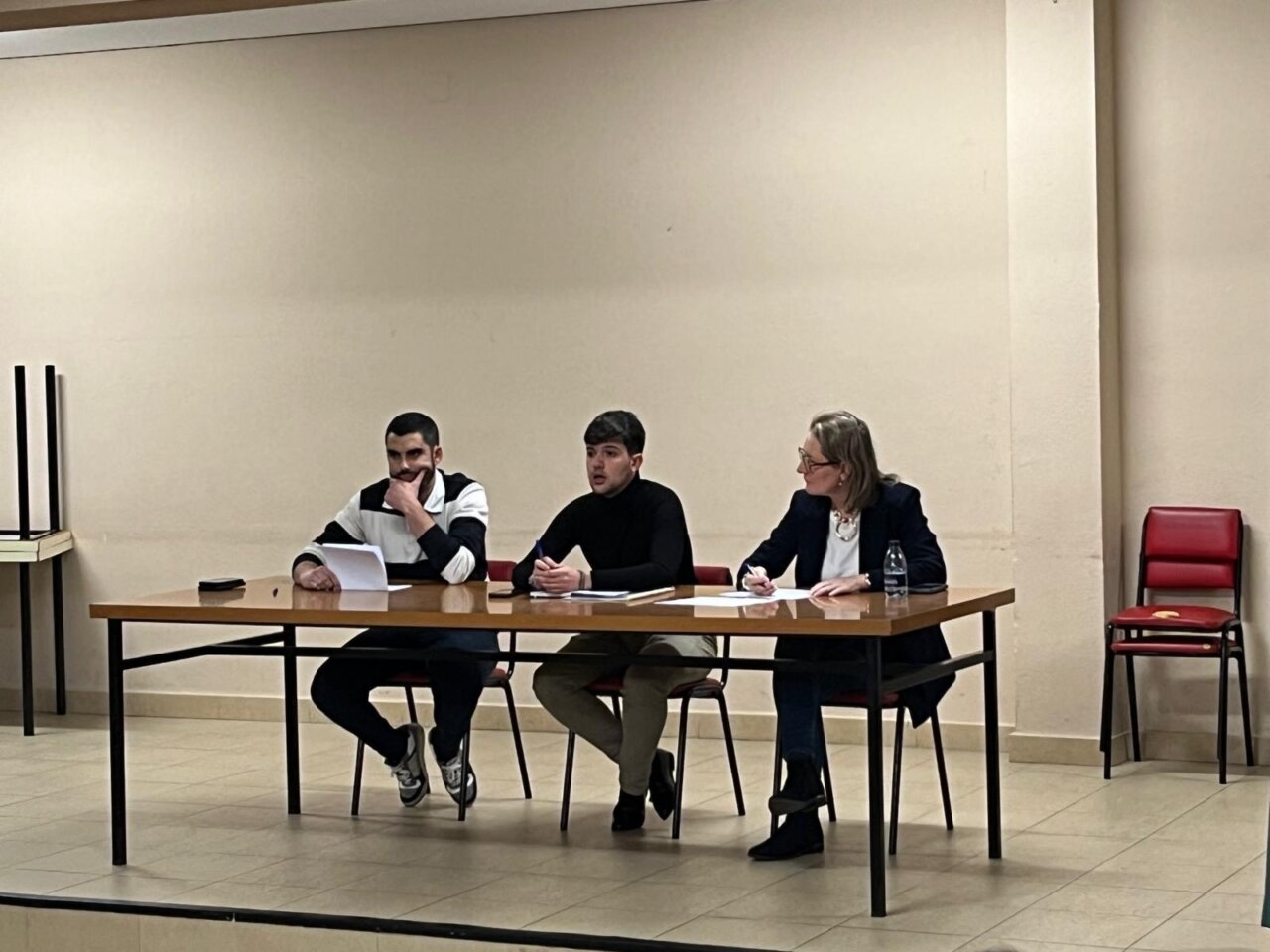 Tres personas sentadas en una mesa durante la asamblea de la AVV San Juanillo.