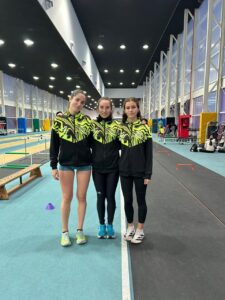 Tres atletas en un gimnasio con ropa deportiva amarilla y negra