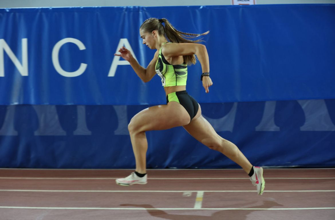 Atleta corriendo en pista cubierta durante competición de atletismo