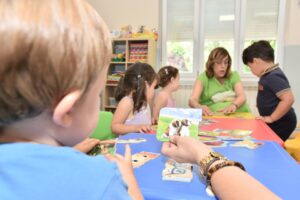 Niños jugando con tarjetas educativas en un aula con una maestra
