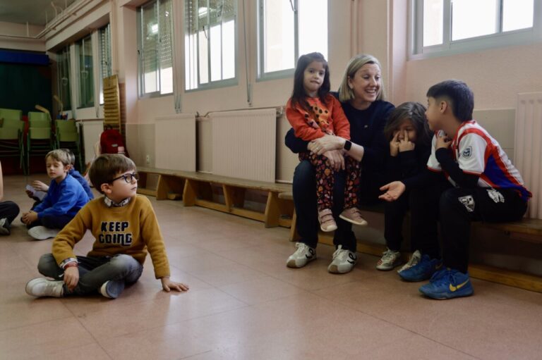 Niños y adultos interactuando en un aula durante la entrega de bonos infantiles