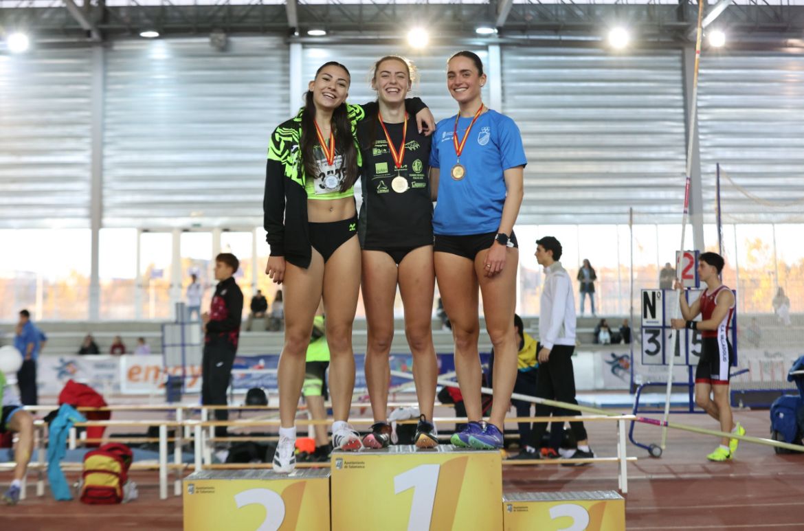 Tres atletas en el podio con medallas tras una competición de atletismo